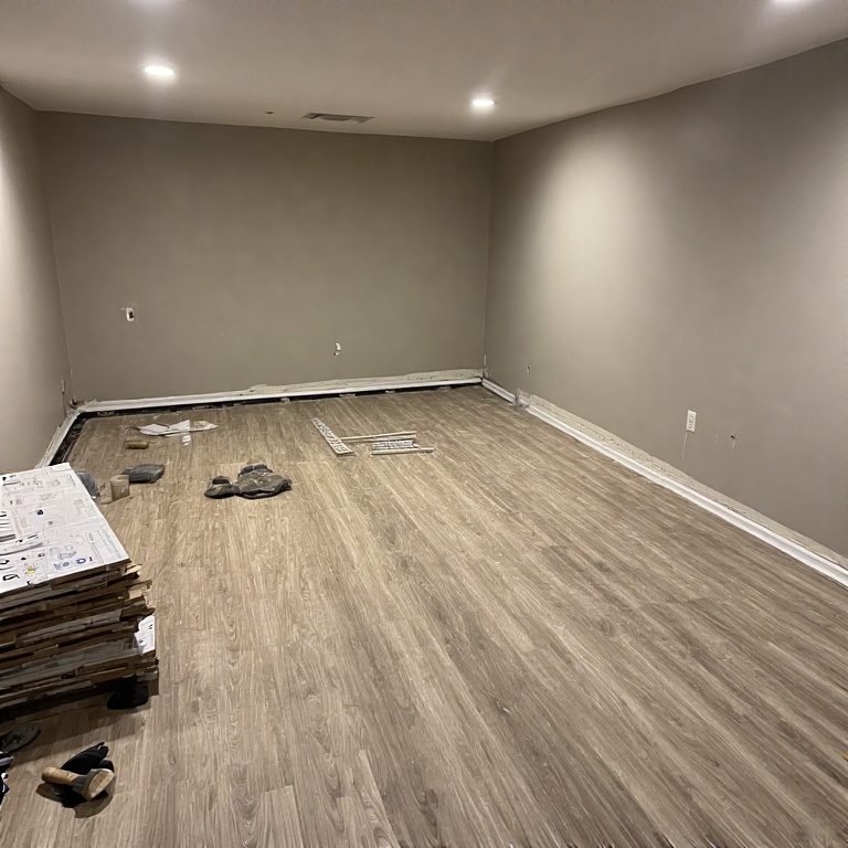Basement Remodeling in Chicago 2 Basement flooring installation with water-resistant vinyl plank flooring, unfinished walls, and construction materials in a newly remodeled space.