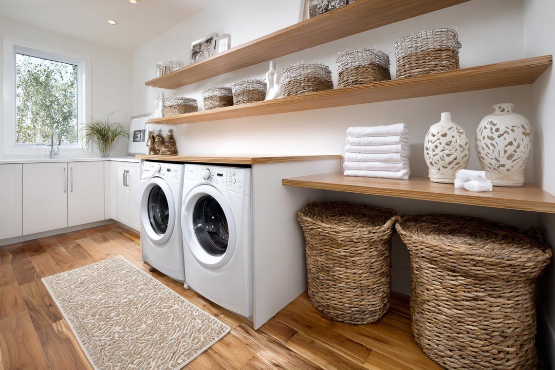 Basement Remodeling in Chicago 17 Laundry room featuring white washing machines, wooden shelving with decorative baskets, neatly stacked towels, and a warm wood floor, illustrating functional design and smart storage solutions for basement remodeling.